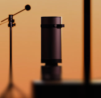 Heatbit Maxi device with a microphone and studio lighting on a brown background